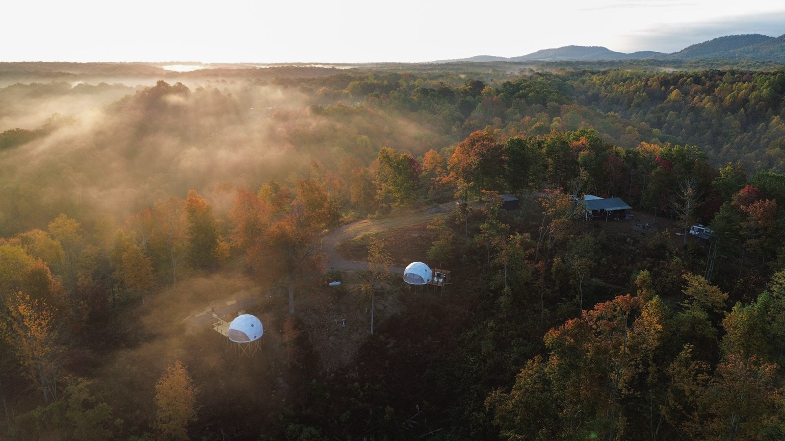 Aerial view of two geodesic domes in misty autumn forest at sunrise, Short Mountain Holiday
