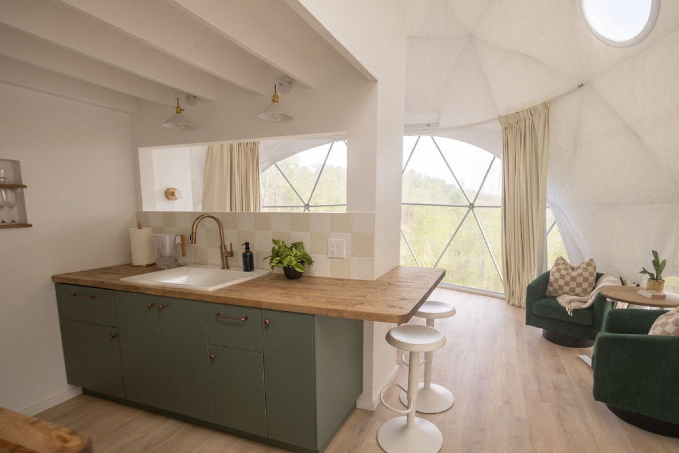 Kitchen with green cabinets and a butcher block counter looking out through the curved geodesic window at Short Mountain Holiday